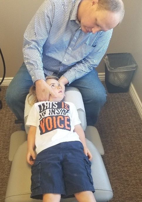 Picture of a little boy being adjusted by a chiropractor